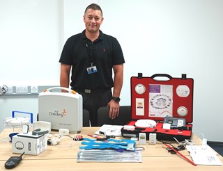JP Pretorius stood in front of a desk with telecare equipment on it.